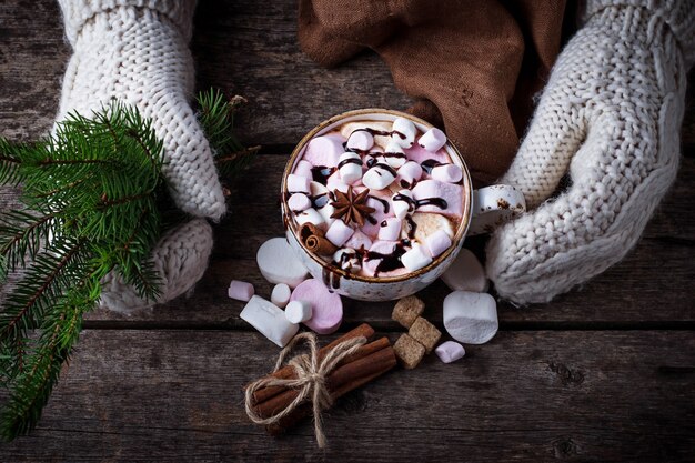 Vrouw in vuisthandschoenen die een kop van hete chocolade met heemst houden. Selectieve aandacht