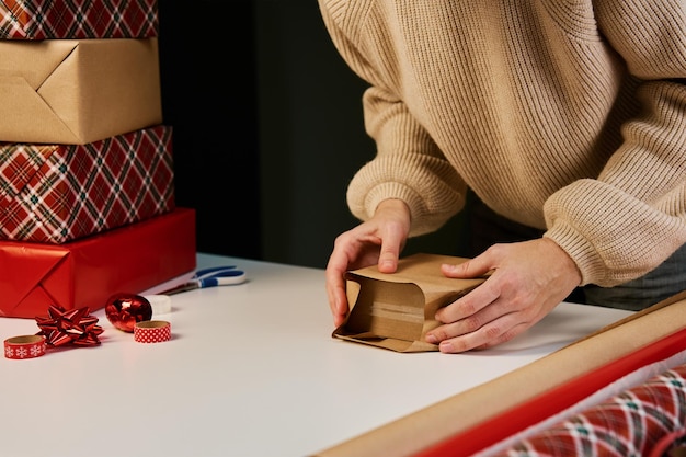 Vrouw in warme trui verpakking geschenkdoos met ambachtelijk papier, cadeau voor verrassing voor vakantie-evenementen