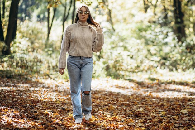 Vrouw in warme trui wandelen in herfst park