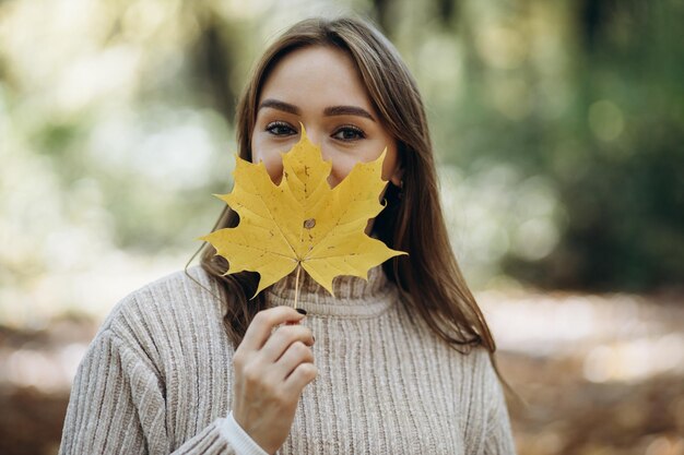 Vrouw in warme trui wandelen in herfst park