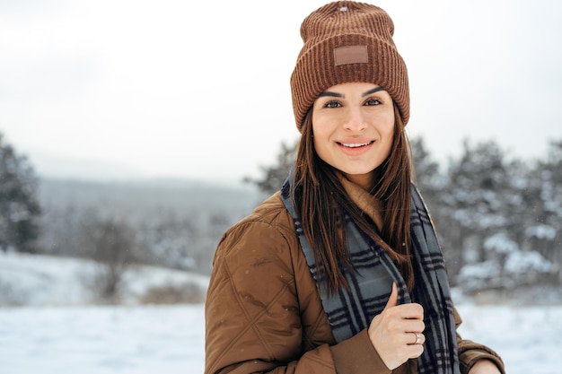 Vrouw in warme winterjas wandelen in besneeuwd winterbos