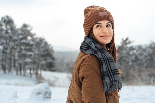 Vrouw in warme winterjas wandelen in besneeuwd winterbos