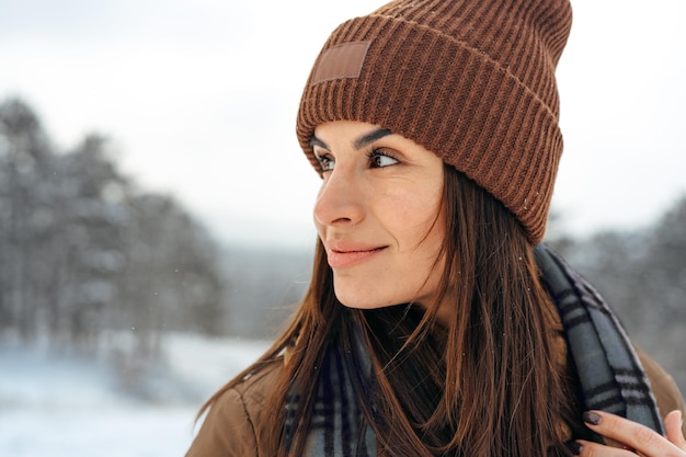 Vrouw in warme winterjas wandelen in besneeuwd winterbos