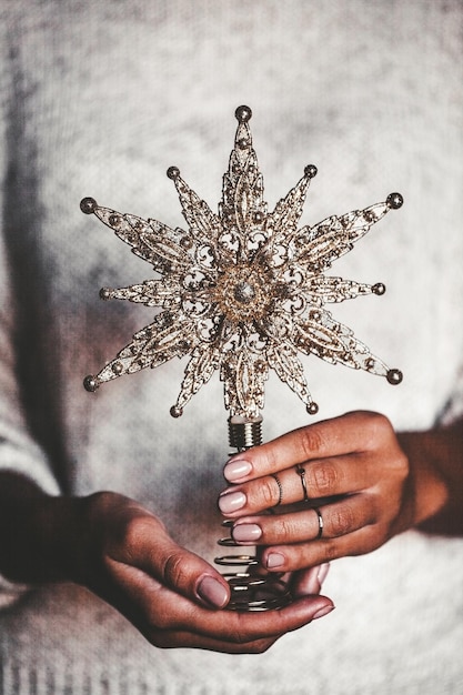 Vrouw in warme wollen trui met speelgoed glazen decoratieve ster in handen, kopieer ruimte, vierkant gewas. Kerstmis, nieuwjaarsconcept voor vakantieviering