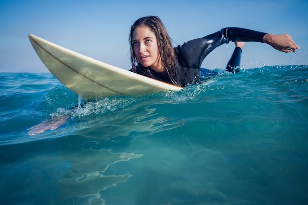 vrouw in wetsuit met een surfplank op een zonnige dag