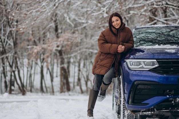 Vrouw in winterbos bij haar auto