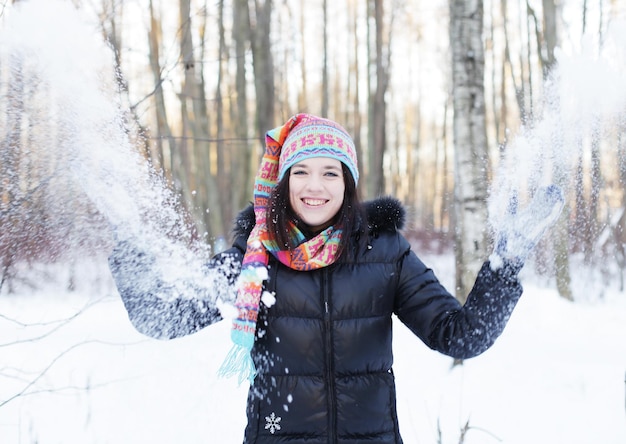 Vrouw in winterpark die speels sneeuw blaast