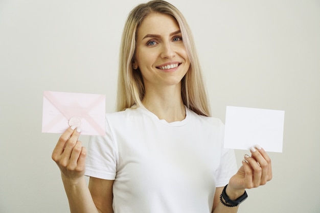 Vrouw in wit t-shirt houdt wit blanco vel papier in de hand