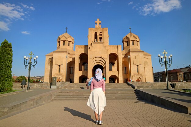 Vrouw in witte hoofdtooi voor de kathedraal van jerevan, jerevan, armenië