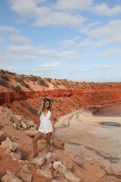 Vrouw in witte jurk kijkend naar de klif met rood zandstrand op Australië