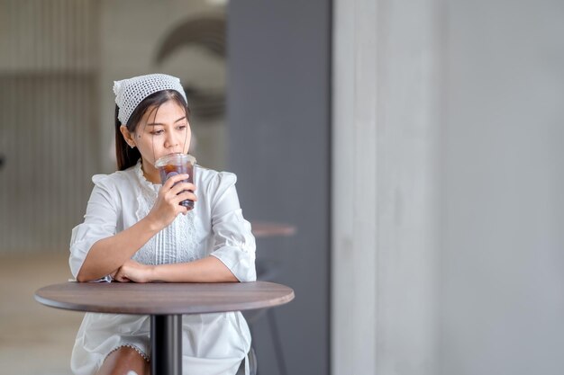 Vrouw in witte jurk zwarte koffie drinken in café