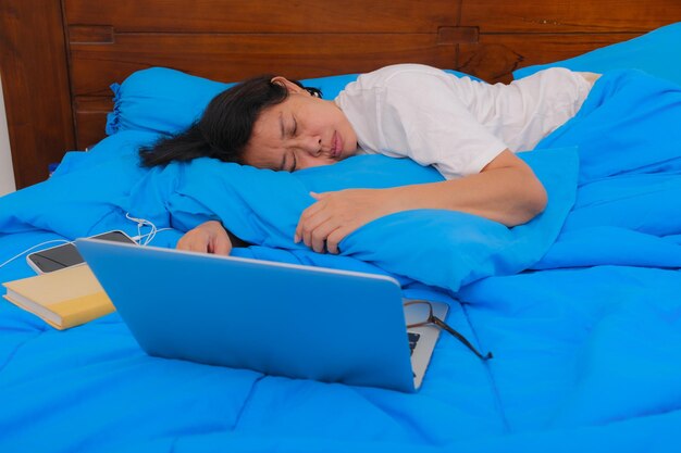 Vrouw in witte t-shirt slapen in blauw laken naast laptopcomputer