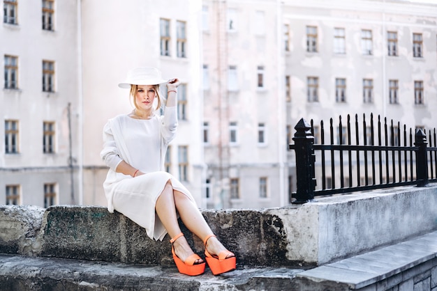 Vrouw in witte vintage jurk buiten zitten