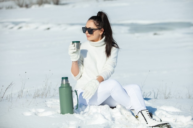 Vrouw in witte winterkleren lopen op een weg omgeven door sneeuw