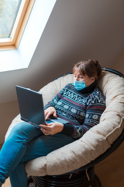 Vrouw in zelfisolatie emote werk op een laptopcomputer zittend in een stoel