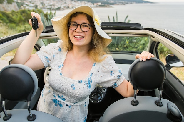 Vrouw in zomer hoed bestuurder met autosleutels rijden haar nieuwe auto cabriolet auto en aankoop concept