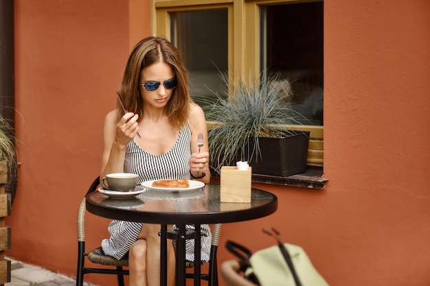 Vrouw in zomerjurk gaat koffiepauze houden op het terras van het café