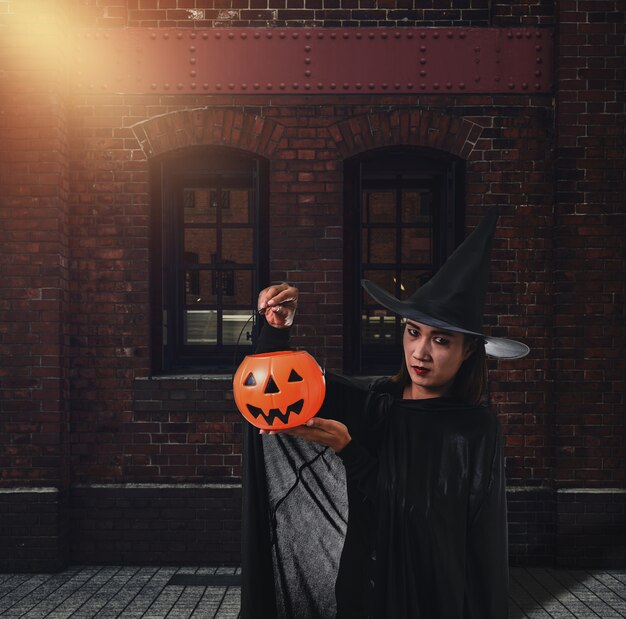 Vrouw in zwart eng heks halloween kostuum met oude bakstenen muur van het oude kasteel van de heks