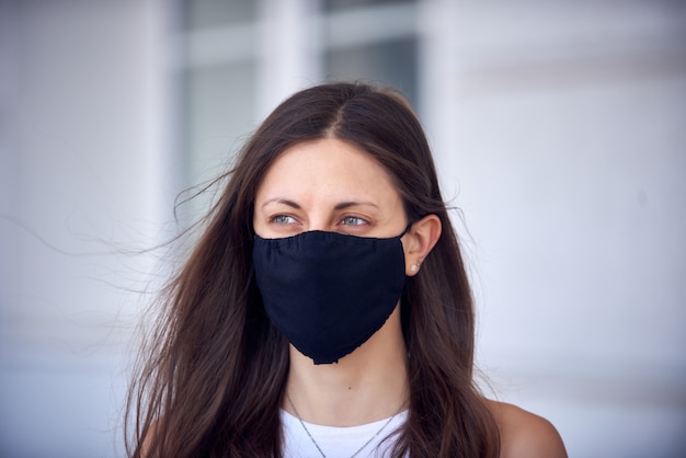 Vrouw in zwart masker op straat als gevolg van epidemie van coronavirus in de stad. Bescherming tegen virussen en infecties