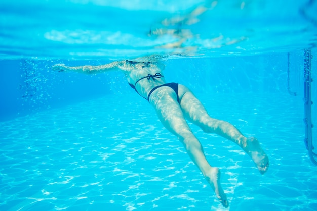 Vrouw in zwarte bikini zwevend bij zwembad