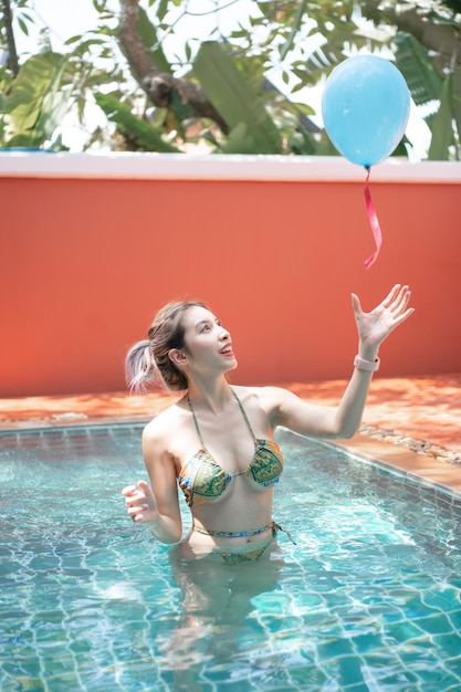 Vrouw in zwembad met plezier met ballonnen.