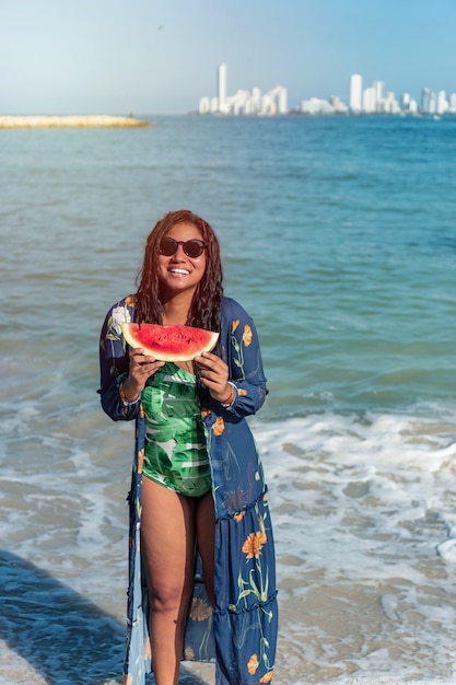 Vrouw in zwembroek met watermeloen op het strand