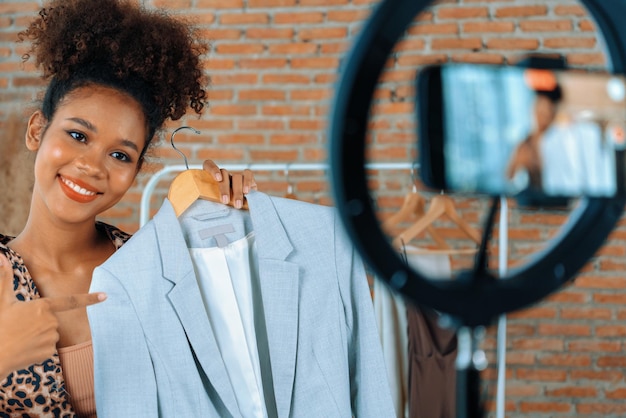 Vrouw influencer schiet live streaming vlog video review kleding cruciale sociale media of blog Gelukkig jong meisje met kleding studioverlichting voor marketing opnamesessie online uitzending