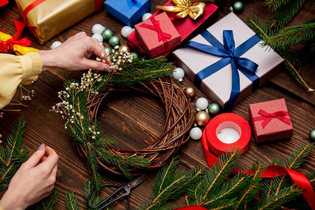 Vrouw is een krans versieren in de buurt van kerstcadeaus