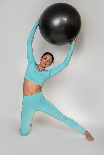 Vrouw is op een fitball en voert oefeningen uit voor de buik en andere delen van het lichaam