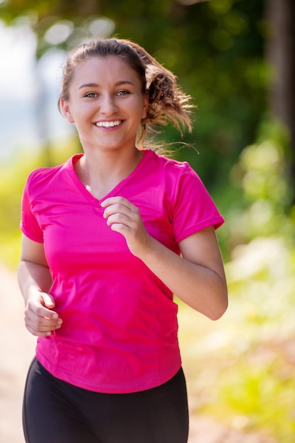 vrouw joggen op een landweg door het prachtige zonnige bos, oefening en fitness concept