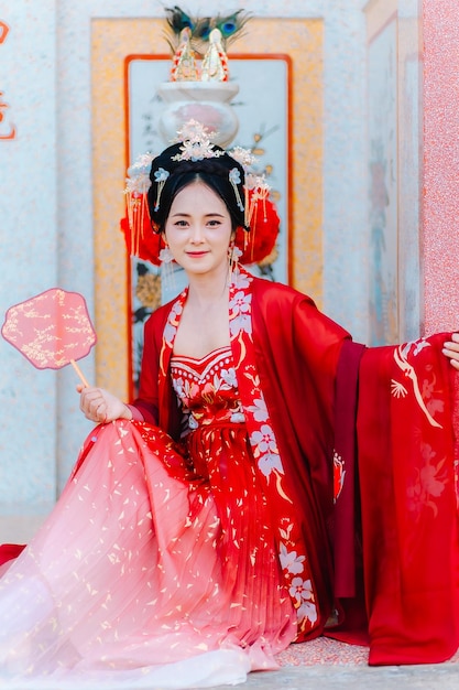 Vrouw jurk China Nieuwjaars portret van een vrouw persoon in traditionele kostuum vrouw in traditionele kostum Mooie jonge vrouw in een felrode jurk en een kroon van de Chinese koningin poseren