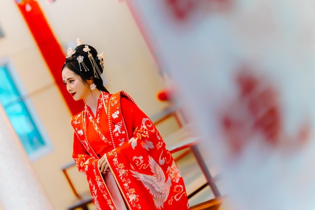 Vrouw jurk China Nieuwjaars portret van een vrouw persoon in traditionele kostuum vrouw in traditionele kostum Mooie jonge vrouw in een felrode jurk en een kroon van de Chinese koningin poseren