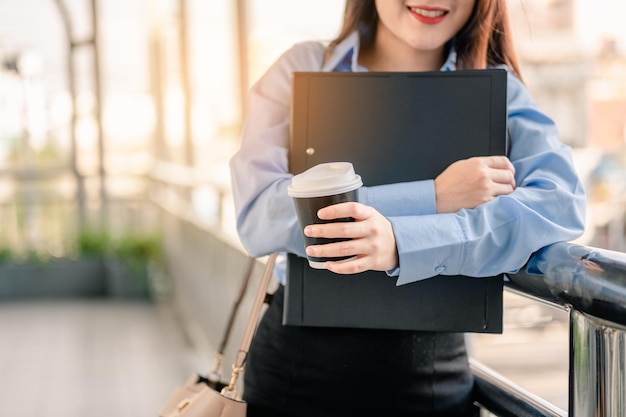 Vrouw kantoormedewerker gaat 's ochtends werken met een bestand en koffie met geluk en frisheid.