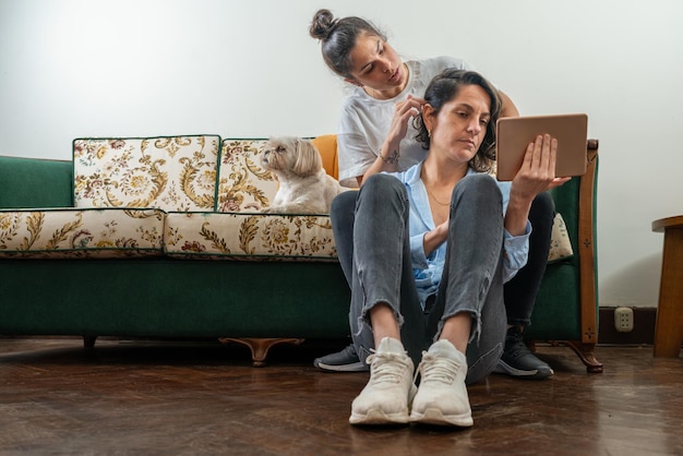 Vrouw kapt het haar van haar partner terwijl hij thuis een tablet gebruikt