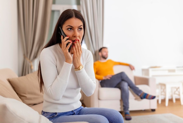 Foto vrouw keerde haar rug naar de man die aan het telefoneren was met haar minnaar, die achterin tv zat te kijken bedrieglijk en ontrouw concept