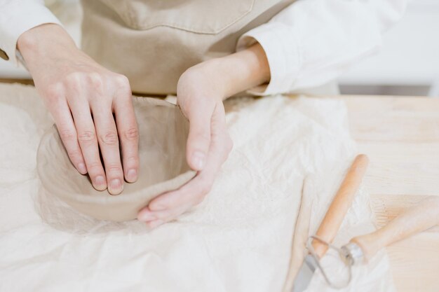 Vrouw keramist in de werkplaats maakt mokken uit klei klein bedrijf of hobby is het maken van keramische producten