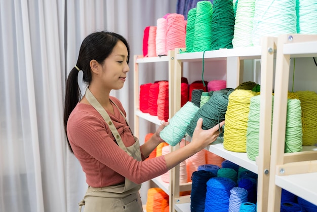 Vrouw kiest de kleur van de draad voor het maken van tufting tapijt in de studio