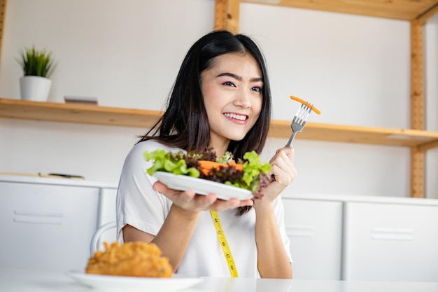 Vrouw kiest ervoor om gezonde groenten te eten en weigert gebakken kip te eten in een goed gezond concept.