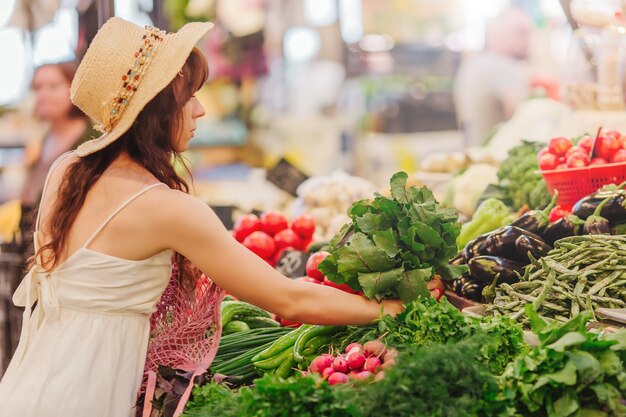 Vrouw kiest groenten en fruit op de voedselmarkt. Herbruikbare eco-tas om te winkelen. Geen afvalconcept.