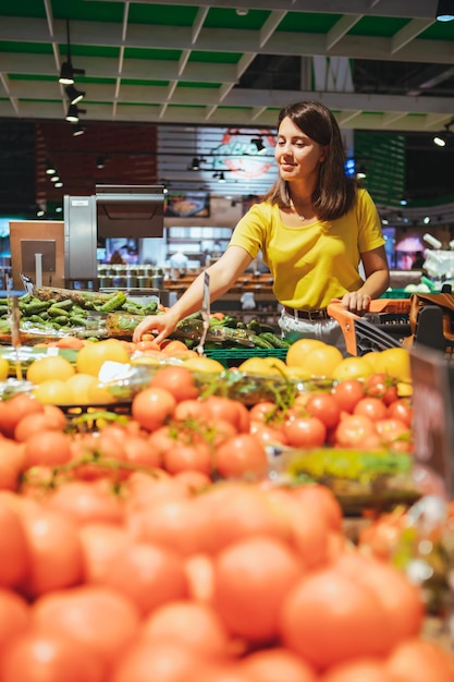 Vrouw kiest rode tomaten uit winkelschap boodschappen doen