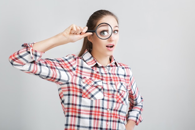 Vrouw kijkt door een vergrootglas