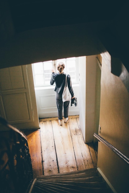 Vrouw kijkt door het raam thuis.