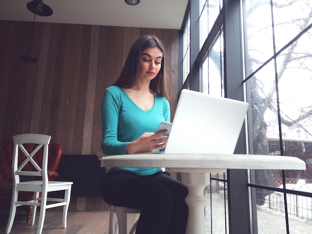 Vrouw kijkt in haar telefoon aan tafel