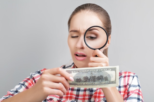 Foto vrouw kijkt in vergrootglas op dollarbiljetten