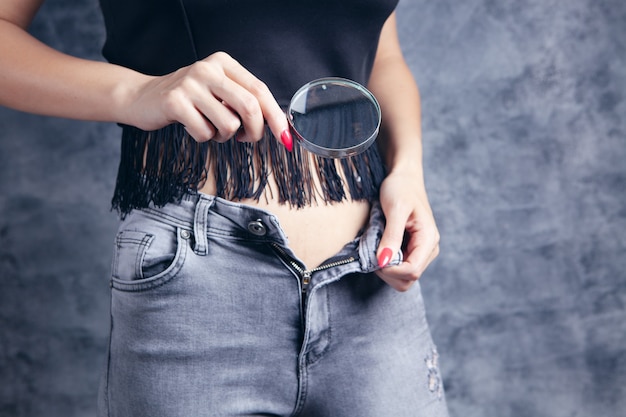 Vrouw kijkt naar de buik met een vergrootglas