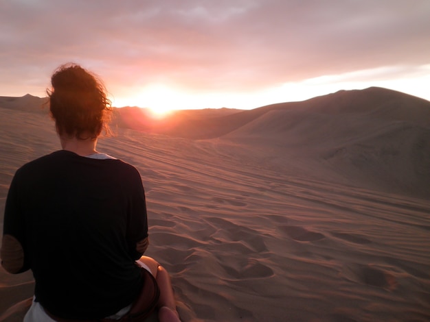 Vrouw kijkt naar de zonsondergang in een woestijn