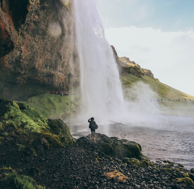 Vrouw kijkt naar een waterval tegen de lucht