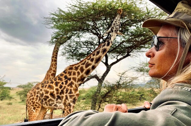 Foto vrouw kijkt naar giraffe door de motorkap