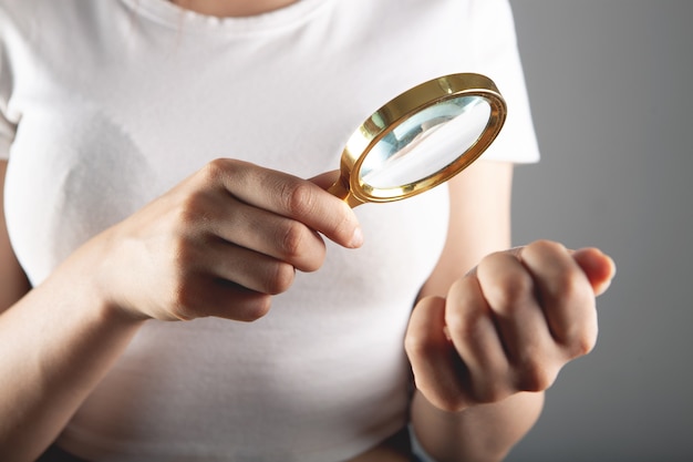 Vrouw kijkt naar haar nagels met een vergrootglas