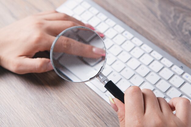 Vrouw kijkt naar het toetsenbord met een vergrootglas